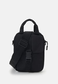 Black fabric crossbody bag with adjustable strap, dual top handles, front flap, zip closure, and a smooth texture. Simple rectangular shape.