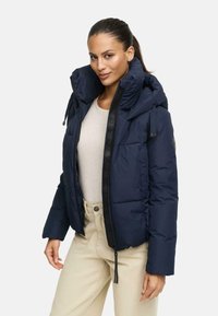 Navy blue padded jacket with a high collar, zip front, and drawstring hood; features black accent details and a logo patch on the sleeve.