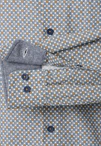 Koszulka z bawełny w wzór z niebiesko-beżowym geometrycznym designem, granatowymi guzikami oraz kontrastowym materiałem w jodełkę na kołnierzyku.