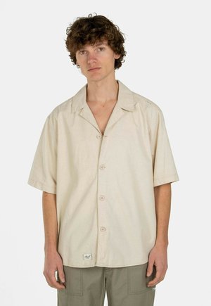 Kurzärmeliges beige Hemd aus leichtem Stoff, mit einer Knopfleiste und einem Patch-Label am Saum, in lässiger Passform.