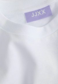 Bijela pamučna majica s okruglim izrezom i rebrastim rubom. Sadrži lavandu oznaku s natpisom "JJXX". Mekana tekstura, strojno ušiveni detalji.