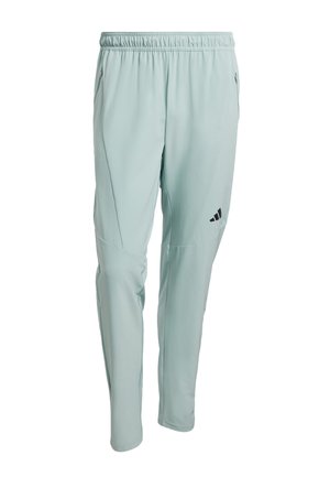 Vaaleanvihreät urheiluhousut, joissa on joustava vyötärönauha, kapenevat lahkeet, sivutaskut ja musta logo vasemmassa reisessä. Pehmeä, joustava kangas.