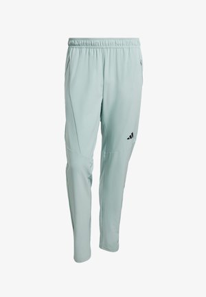 Vaaleanvihreät urheiluhousut, joissa on joustava vyötärönauha, kapenevat lahkeet, sivutaskut ja musta logo vasemmassa reisessä. Pehmeä, joustava kangas.