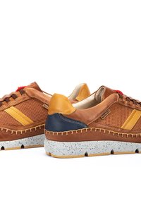 Sneaker in pelle marrone con accenti gialli, lati perforati, tallone in contrasto blu navy e suola intermedia maculata. Presenta dettagli di cucitura visibili.