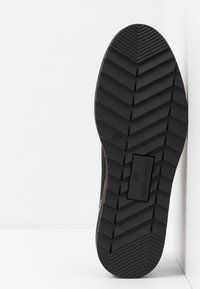 Semelle d'une chaussure noire montrant un motif en chevrons, taille 37, et la marque "Anna Field" au bas.