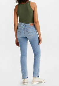 Jean en denim bleu clair avec une coupe slim, une taille haute et des coutures contrastées. Comprend des poches arrière classiques et un patch Levi's.