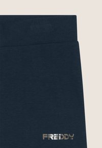 Pantaloni tuta blu navy con cintura a coste e logo lucido "FREDDY" in argento sulla gamba sinistra, realizzati in morbido tessuto testurizzato.