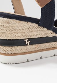 Námořnické modré platformové sandály s tkaným jutovým svrškem, které mají hnědý kožený akcent, gumovou podešev a kovový detail loga na pásku.