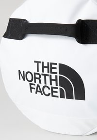White bag with black top handle and black "The North Face" logo on the front.