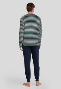 Conjunto de ropa de estar en casa para hombres que incluye una camiseta de manga larga a rayas en verde y marino con dobladillos laterales, combinada con pantalones ajustados sólidos en color marino con puños en los tobillos.