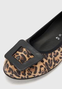 Ballerine con stampa leopardata realizzate in morbido suede, con un accento in pelle nera a forma quadrata sulla punta e un bordo elastico nero attorno all'apertura.