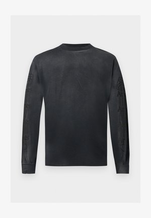 T-shirt noir à manches longues avec col rond et un discret motif de texte sombre le long des deux manches, présenté sur un fond clair uni.