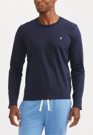 Marineblauwe katoenen shirt met lange mouwen, ronde hals en logodetail. Zachte textuur, aansluitend ontwerp, gecombineerd met lichtblauwe broek.