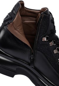 Botas de cuero negro y fieltro gris con cierre de cremallera, parte frontal con cordones, detalles en metal plateado y forro interior texturizado.