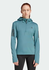 Teal atletisk hoodie med halvdragkedja, justerbar huva och svarta tre-stripes accentuerar ärmarna. Slät textur, figurnära design.