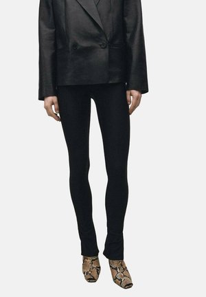 Zwarte, aansluitende legging gecombineerd met een zwart leren blazer met dubbele knopen. Het model heeft bruine enkellaarsjes met slangenprint aan.
