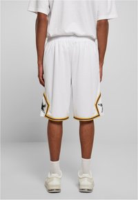 Baltie basketbola šorti ar dzelteniem un melniem akcentiem, kuriem tuvumā pie apakšmala ir zvaigžņu raksts. Elastīga jostasvieta komfortam.