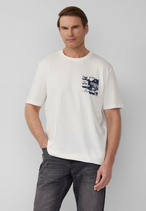 Witte katoenen t-shirt met korte mouwen, voorzien van een blauw grafisch ontwerp op de linkerkant van de borst. Gepaard met donkergrijze versleten jeans.