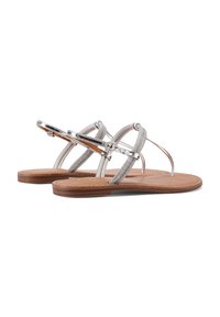 Sandali con cinturini e dettagli metallici argento, cinghie beige e una suola piatta marrone. Materiale in tessuto e finta pelle, design minimalista.