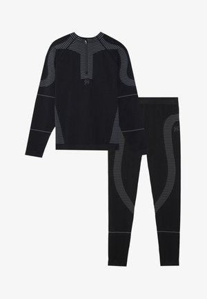 Haut de sport noir à manches longues avec col zippé et accents rayés, associé à un pantalon ajusté assorti avec des motifs de rayures contrastés.
