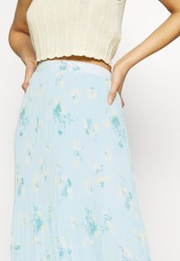 Light blue pleated skirt, featuring floral patterns in yellow and green. Made of soft fabric with an elastic waistband for comfort.