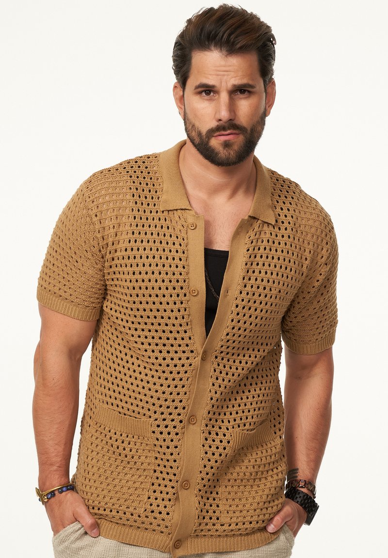 Strickjacke mit kurzen Ärmeln in Hellbraun, offenes Muster, Knopfverschluss, zwei vordere Taschen sowie gerippter Kragen und Ärmel.