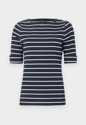 Granatowa koszula z krótkim rękawem z białymi poziomymi paskami i okrągłym dekoltem na jasnoszarym tle.