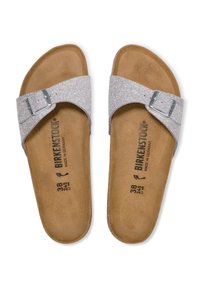 Sandalias de purpurina plateada con una correa con hebilla, plantilla de corcho y suela interior de suave marrón. Marcadas con la marca "Birkenstock" y detalles de tamaño.