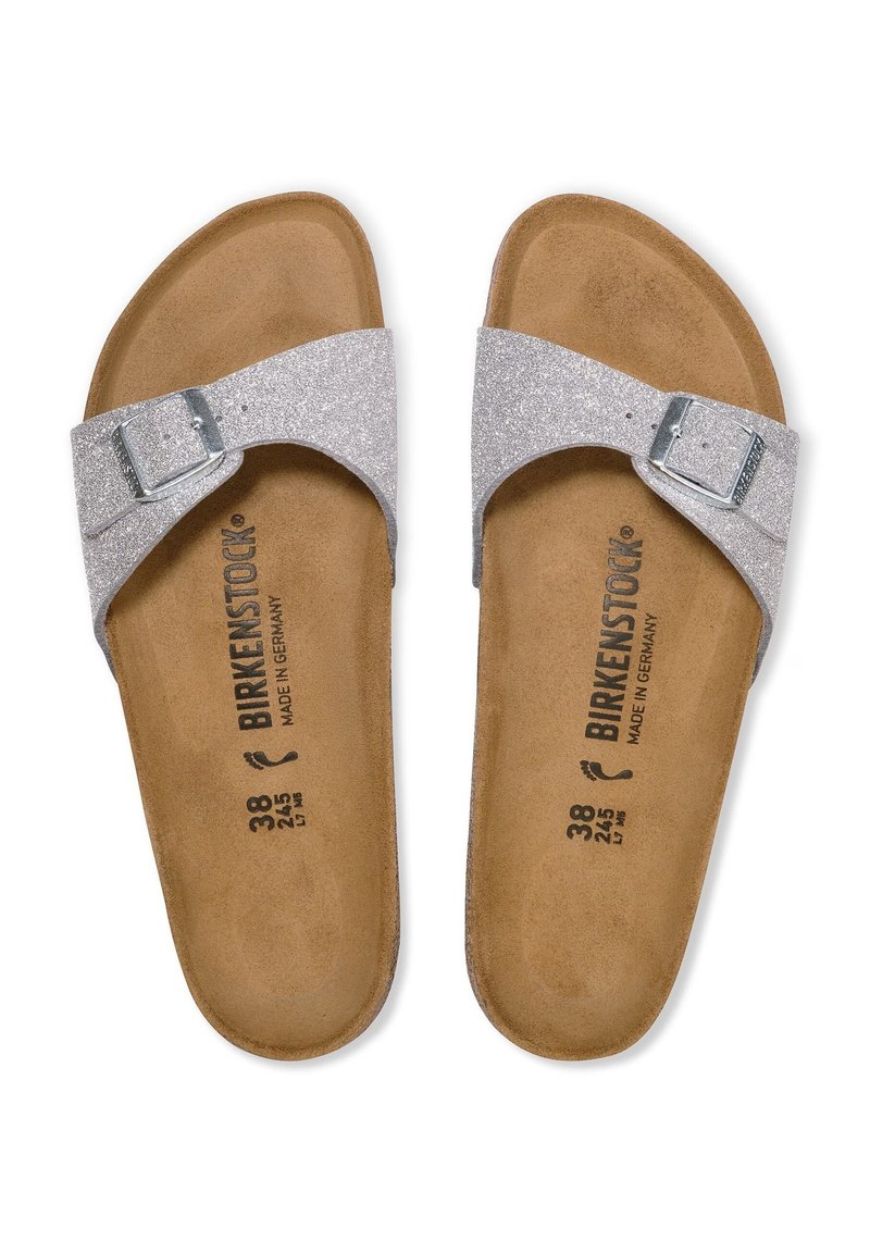 Sandales scintillantes argentées avec une bride à boucle, semelle en liège et semelle intérieure douce marron. Marquées avec le logo "Birkenstock" et les détails de taille.