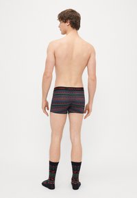 Fekete és piros mintás boxeralsó ünnepi dizájnnal és fekete gumírozott derékrésszel, rajta a "JACK & JONES" logó; passzoló zoknikkal viselve.