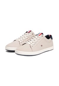 Sneakers in tela beige con lacci bianchi, dettagli blu navy e una piccola patch con logo. Suola piatta in gomma e design basso per un look casual.