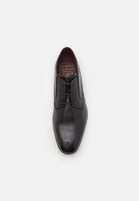 Zapato de vestir negro de cuero con un acabado pulido, puntera afilada, diseño de cordones y costuras tonales sutiles en la parte superior.