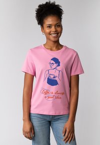 Roze katoenen t-shirt met een blauwe geïllustreerde afbeelding van een vrouw die een kopje vasthoudt, met de tekst "Koffie is altijd een goed idee" in oranje.