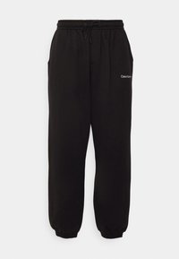 Μαύρες φόρμες από μαλακό ύφασμα, με ελαστική μέση και κορδόνι, πλαϊνές τσέπες και μίνιμαλ λογότυπο σε λευκό χρώμα.