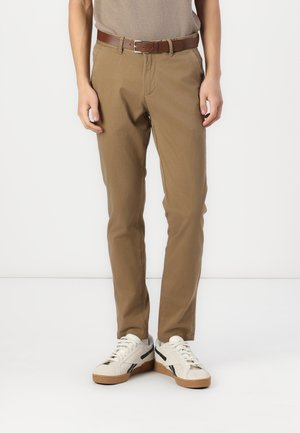 Slim-fit, beige chinos, featuring a classic design with front pockets and a brown belt. Paired with white sneakers, showcasing black accents.
