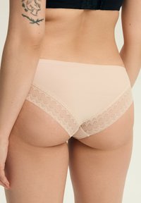 Nude Damen-Hipster-Unterwäsche aus glattem Stoff mit Spitzenbesatz an den Rändern, in modischer Schnittform und nahtlosem Design.