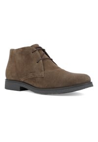 Boots homme en daim marron à lacets, semelle noire, bout légèrement pointu et embossage discret de la marque sur le côté.