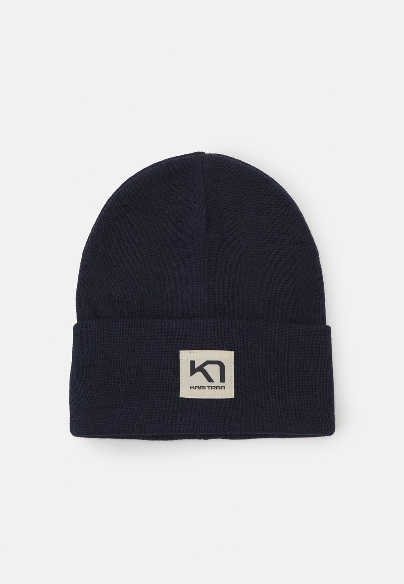 Merinovillainen tummansininen beanie, jossa on taitettu reuna ja neliön muotoinen etiketti, jossa on musta logo. Valmistettu pehmeästä kankaasta, jolla on sileä pinta.