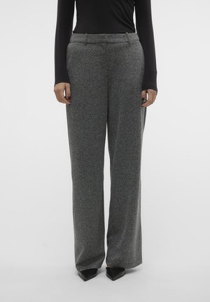 Woman wearing high-waisted, wide-leg gray trousers with subtle herringbone pattern, black pointed shoes, and a fitted black long-sleeve top.