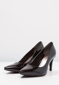 Schwarze Lackleder-Pumps mit einer spitzen Zehenform und einem schlanken Stiletto-Absatz, die eine glatte, glänzende Oberfläche aufweisen.