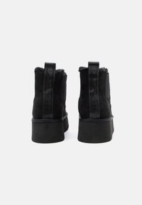 Pair of black suede platform boots with thick soles, fur lining visible at the top, and branded pull tabs at the back.