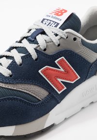 New Balance 997H sneakers med en blandning av marinblå mocka, grå syntetiska detaljer och röd logotyp. Texturerade ytor med vita snören och sömlös.