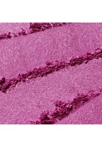Maquillage en poudre rose éclatante écrasée avec des stries diagonales texturées sur une surface plane, montrant des particules fines et grossières.