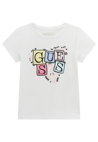 Camiseta blanca de manga corta hecha de algodón orgánico, con un gráfico colorido en letras de bloque que dice "GUESS", acompañado de bocetos y acentos de texto juguetones.