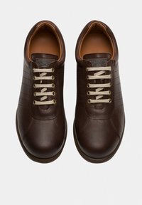 Brown leather sneakers with a smooth texture, featuring five pairs of eyelets, light beige laces, and a cushioned tan interior.