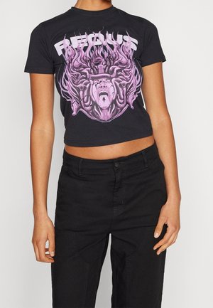 Zwarte cropped t-shirt met een roze afbeelding van een schreeuwend gezicht met vloeiend haar en de tekst "Furious", gedragen met zwarte hoge taillebroek.