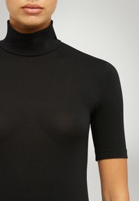 Top nero, con collo alto e maniche corte, realizzato in tessuto morbido e stretch con una silhouette aderente. Design minimalista, senza motivi visibili.