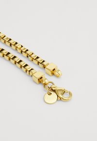 Goldkette mit quadratischen Gliedern, ausgestattet mit einem Karabinerverschluss und einem runden Anhänger. Die Oberfläche hat ein poliertes Finish und eine reflexive Textur.