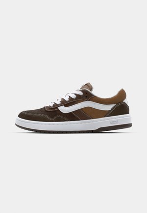 Brązowe zamszowe sneakersy z białymi akcentami i sznurówkami, z wyściółką przy kołnierzu, zaokrąglonym noskiem oraz teksturowaną gumową podeszwą.
