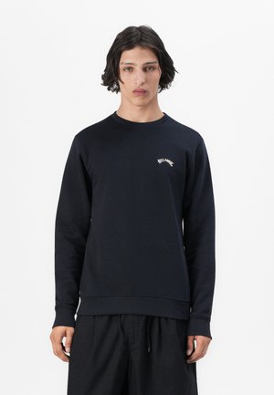 Navy blue sweatshirt with long sleeves, ribbed cuffs, and hem. Features a small white logo on the chest. Made from a soft fabric.